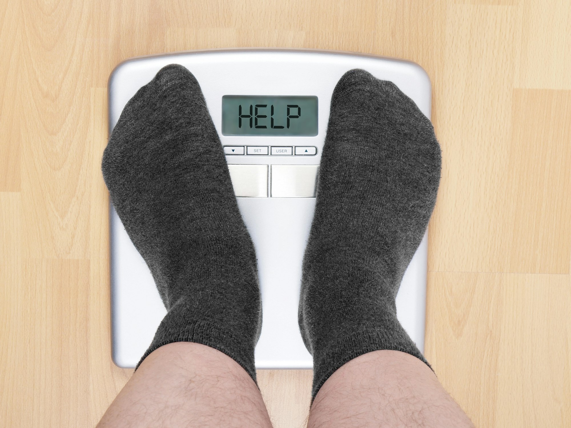 overweight man on personal scales, display cries for help