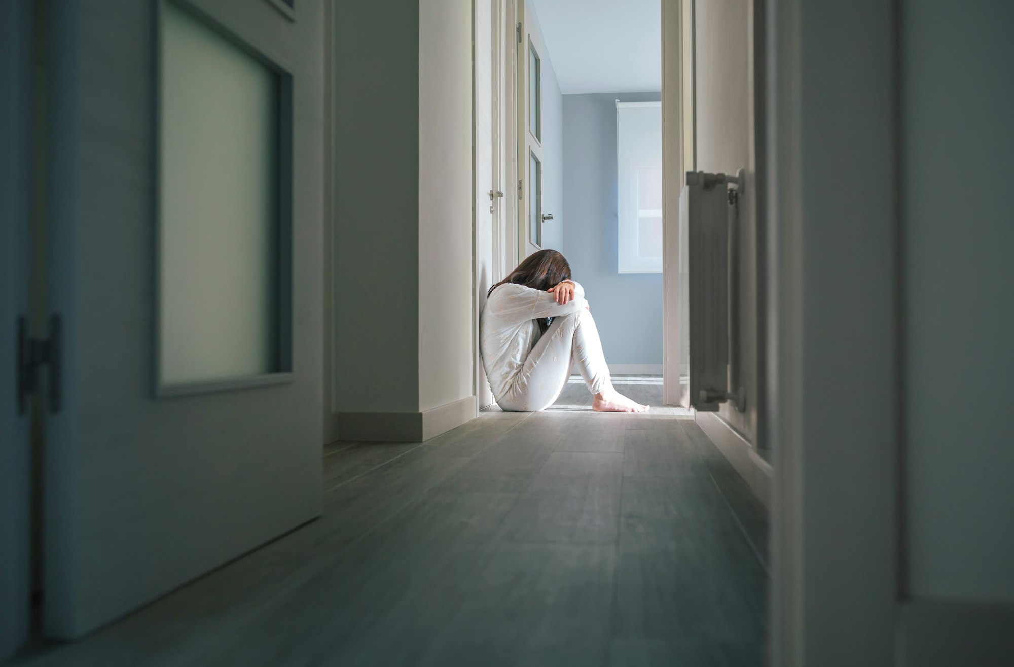 Woman in pajamas sitting on the floor of a mental health center